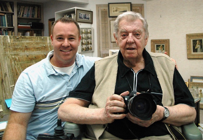 A man and an older gentleman holding a camera.