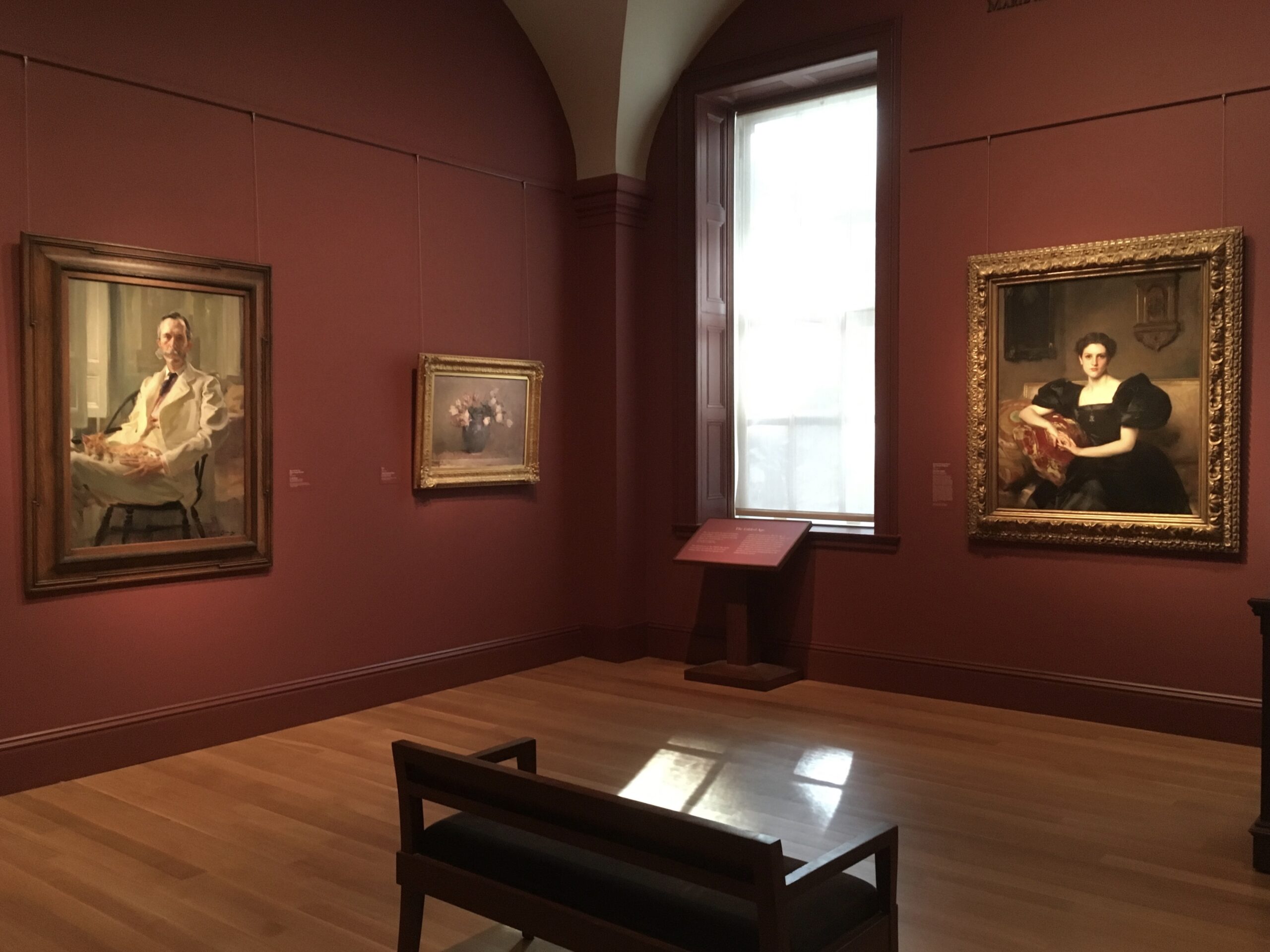 A room with two paintings and a bench in it