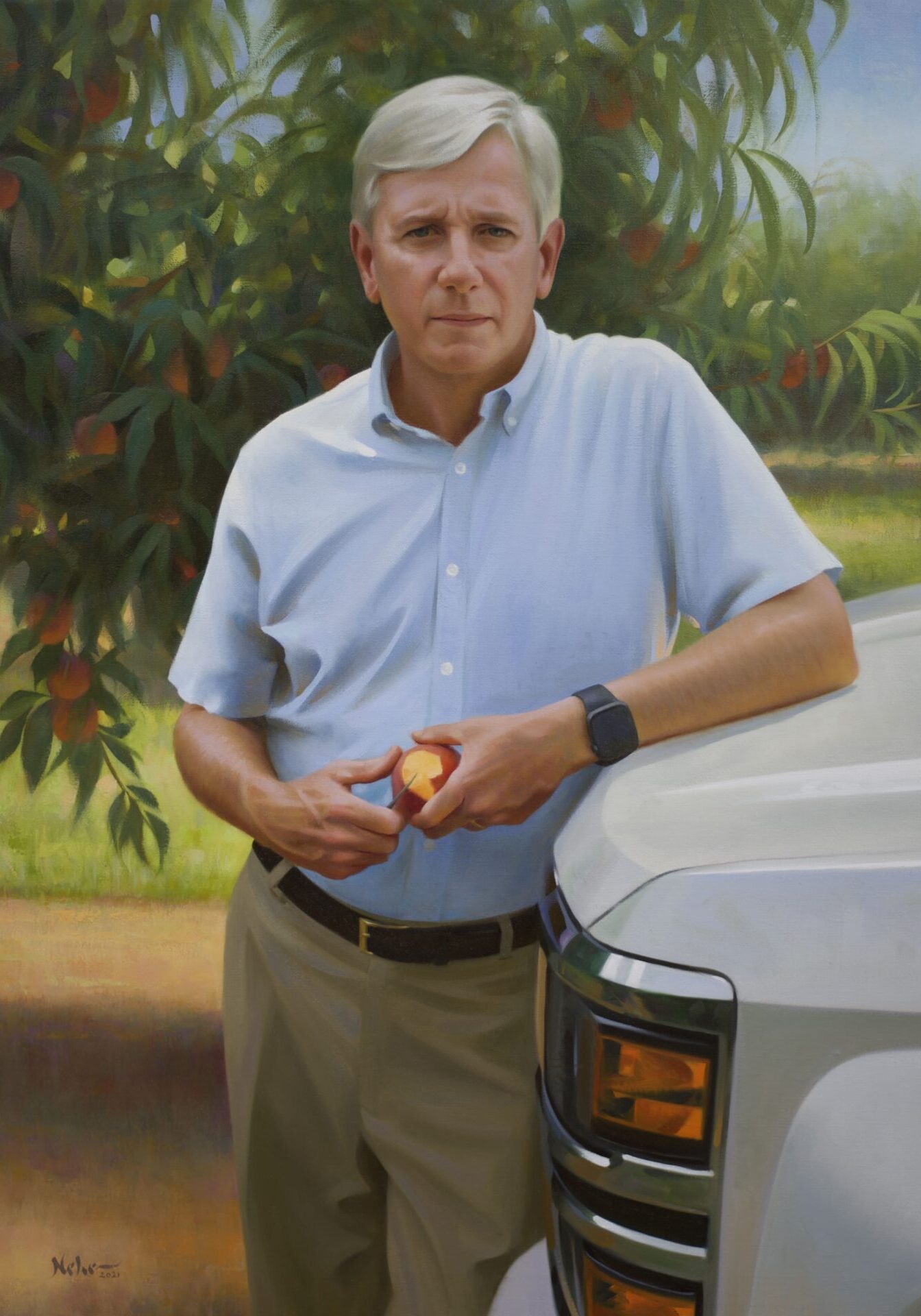 A man holding an apple in front of a truck.